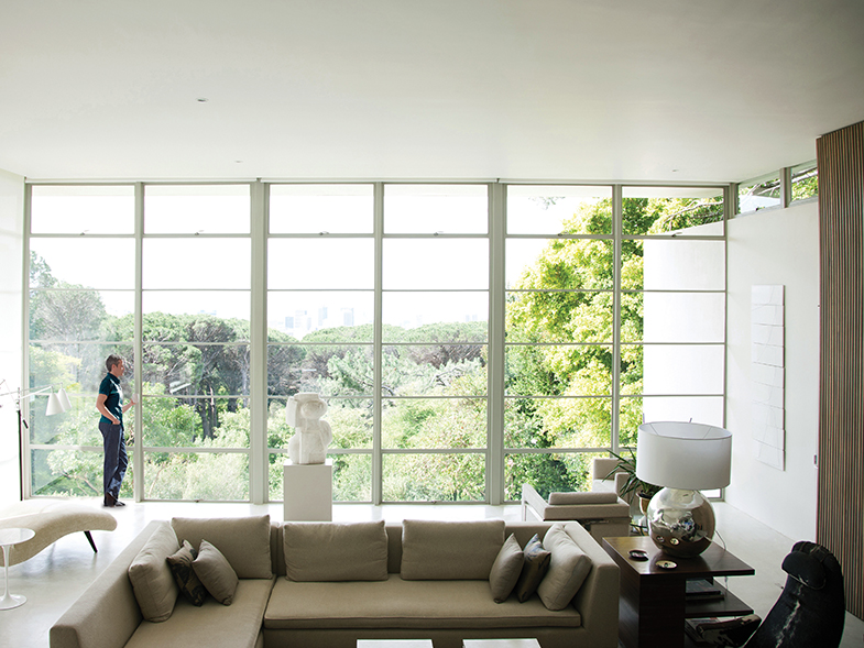 Living Room with large window overlooking wooded area man on left
